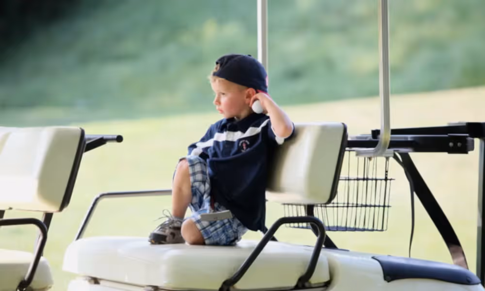 Young boy sitting in the back of a golf cart