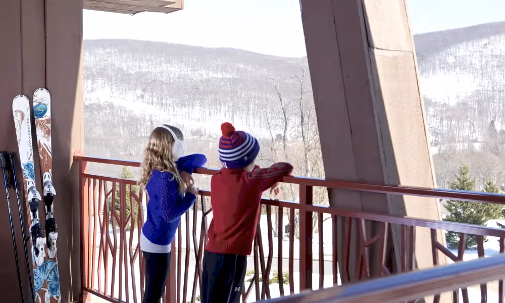 Children overlooking the snowy mountain view from balcony at Grand Cascades Lodge 